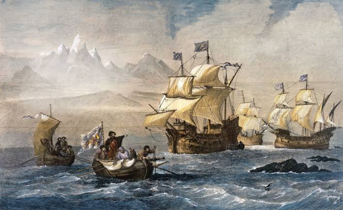 Sailing ships at sea beneath snowy mountains